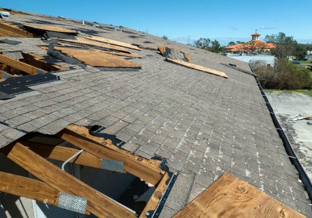 Hurricane roof damage on a New Orleans home showing lifted shingles and exposed decking
