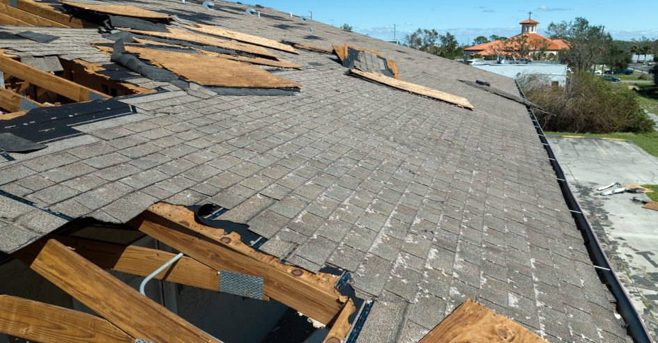 Hurricane roof damage on a New Orleans home showing lifted shingles and exposed decking