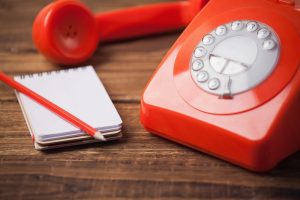 Red landline phone, notepad on the side